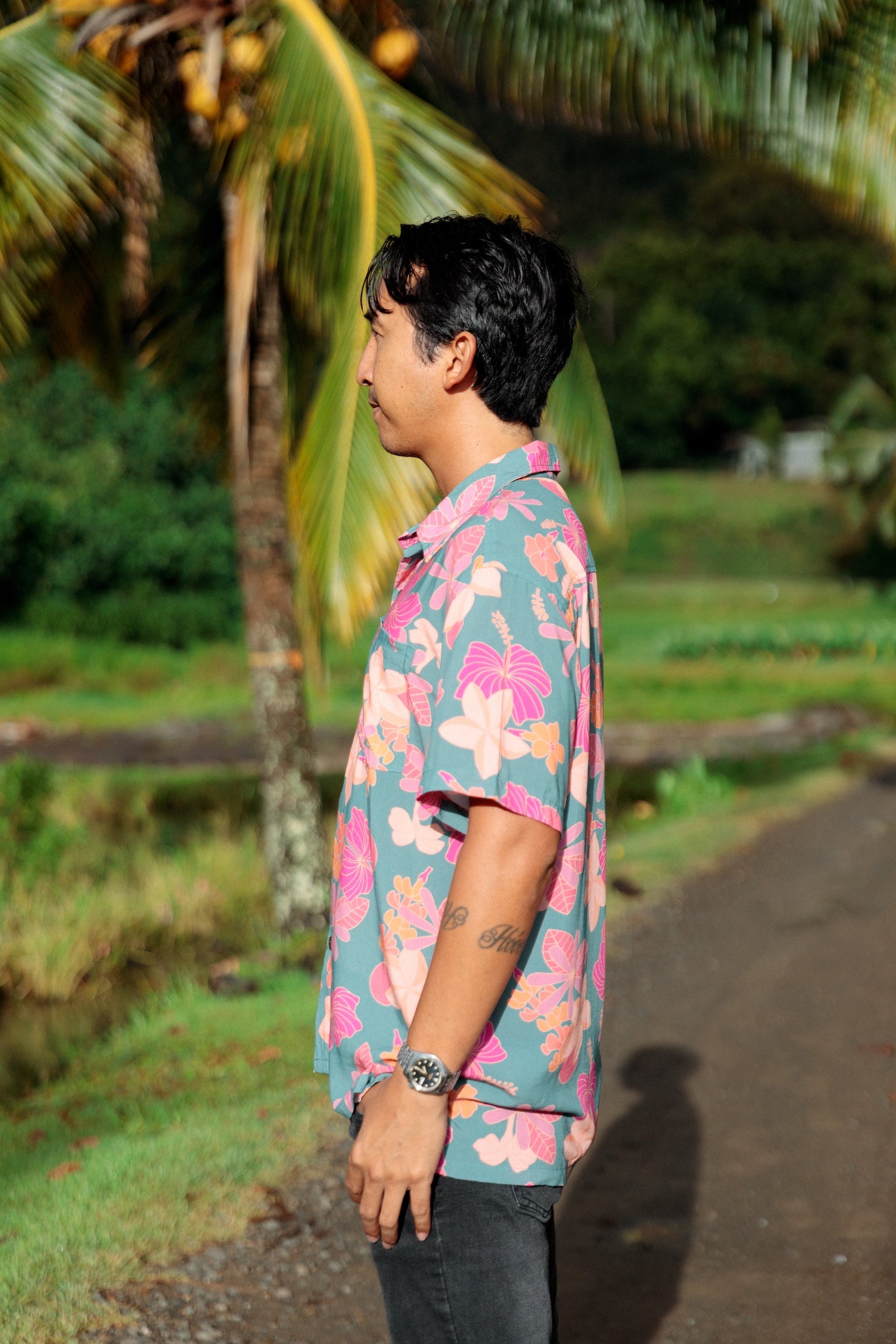 man wearing a teal aloha button up shirt with pink and orange floral pattern
