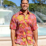 man wearing terracotta colored aloha shirt with large purple and yellow flower print