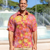 man wearing terracotta colored aloha shirt with large purple and yellow flower print