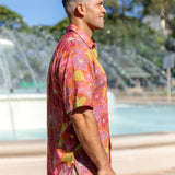 man wearing terracotta colored aloha shirt with large purple and yellow flower print