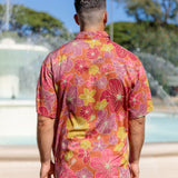 man wearing terracotta colored aloha shirt with large purple and yellow flower print