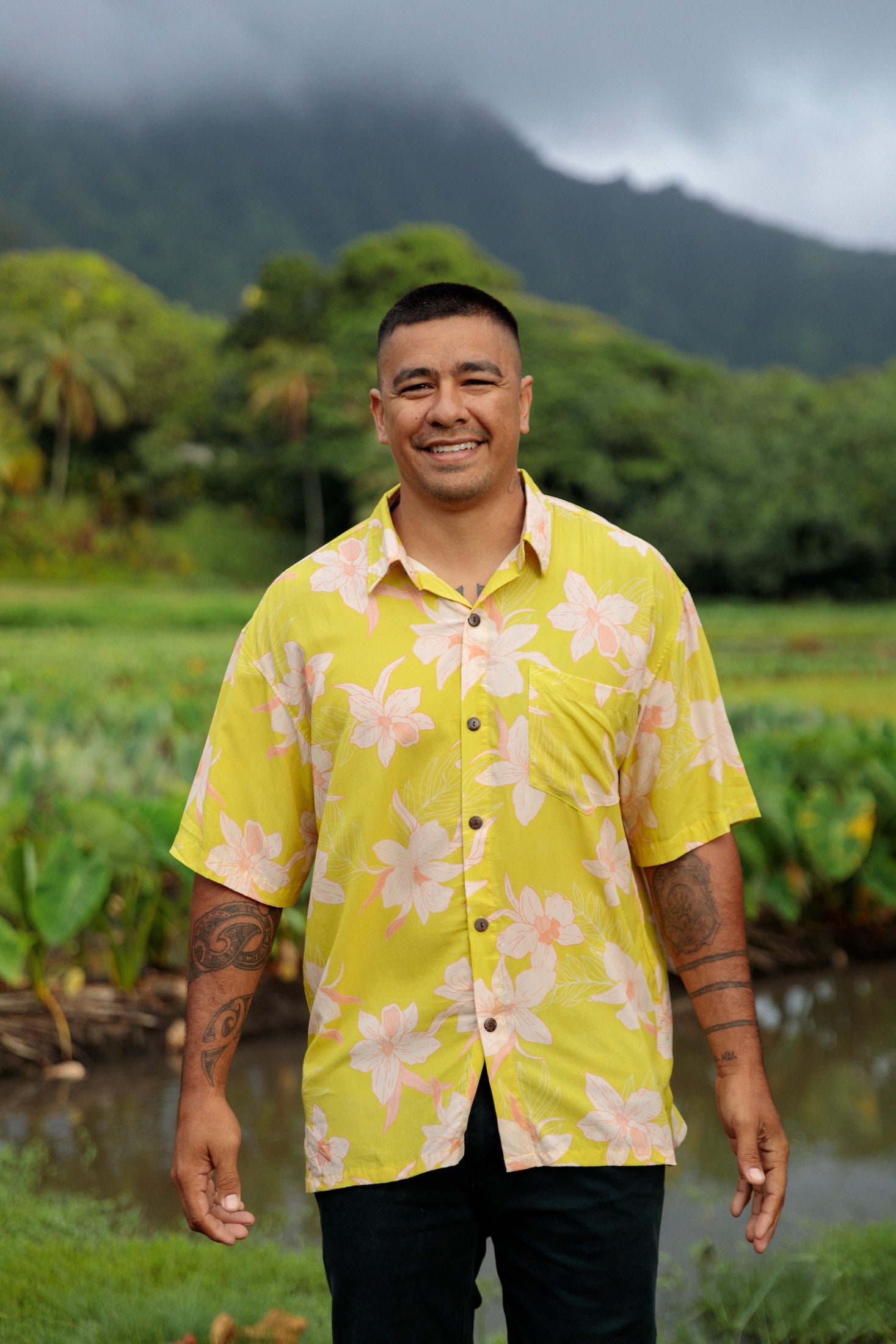man wearing bright yellow green aloha button up shirt with orchid print 