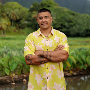 man wearing bright yellow green aloha button up shirt with orchid print 