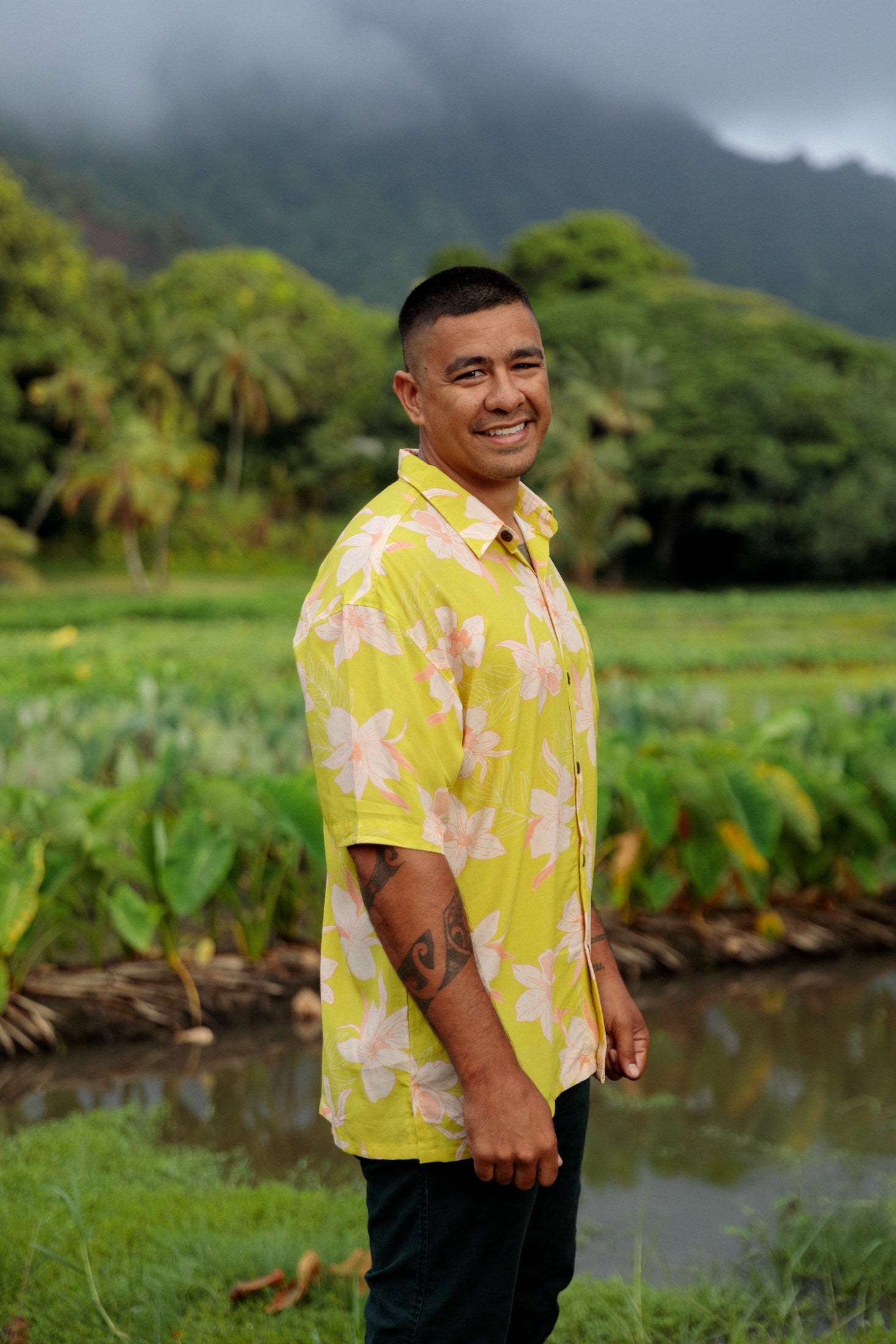 man wearing bright yellow green aloha button up shirt with orchid print 