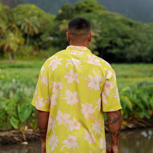 man wearing bright yellow green aloha button up shirt with orchid print 
