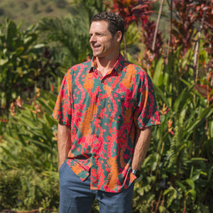 man with brown hair wearing a colorful button up aloha shirt with tropical lei print