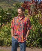 man with brown hair wearing a colorful button up aloha shirt with tropical lei print