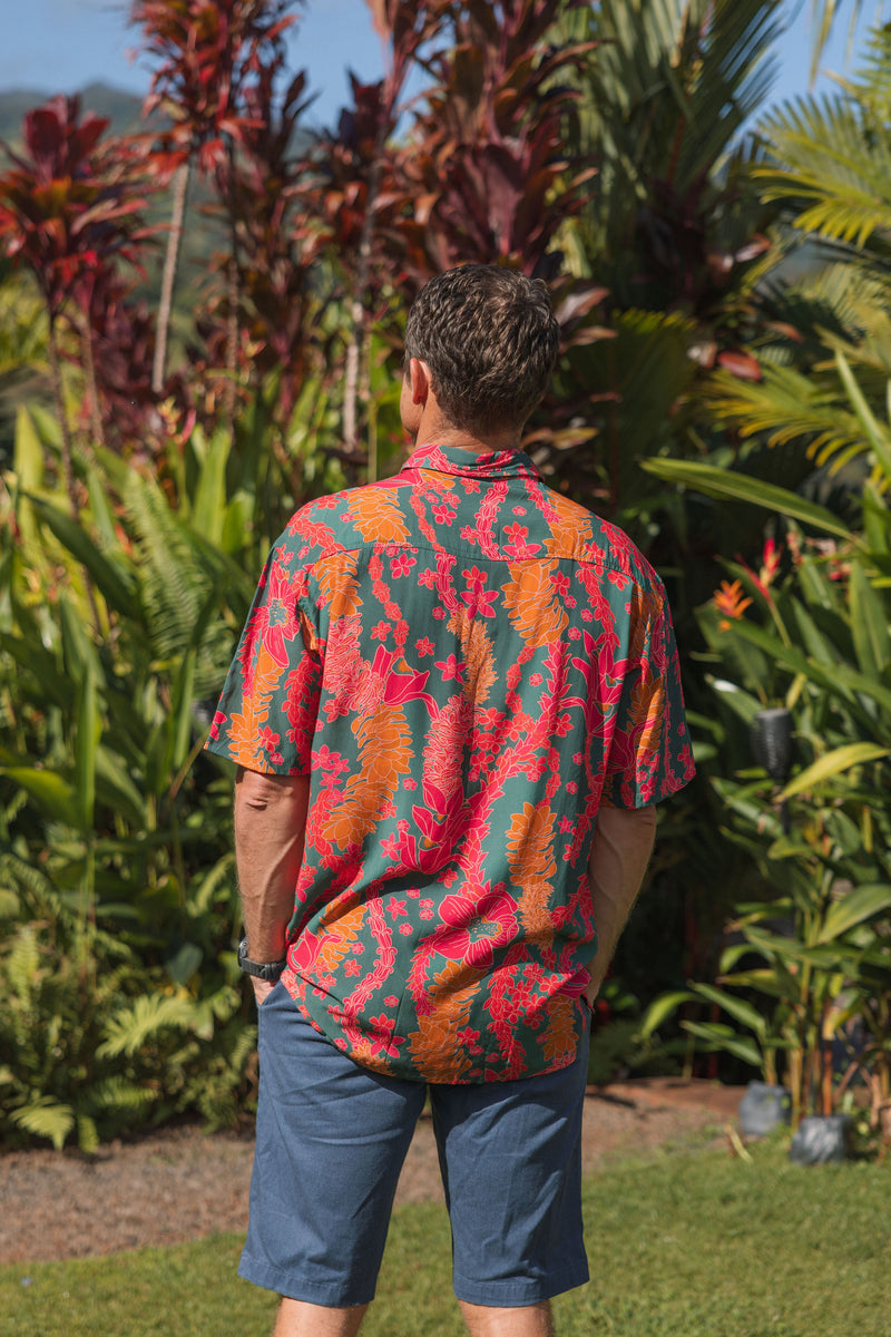 man with brown hair wearing a colorful button up aloha shirt with tropical lei print