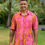 man wearing pink aloha button up shirt with lei strands