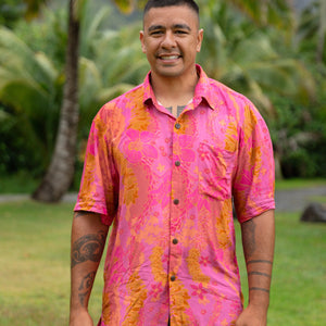 man wearing pink aloha button up shirt with lei strands