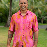man wearing pink aloha button up shirt with lei strands