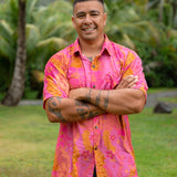 man wearing pink aloha button up shirt with lei strands