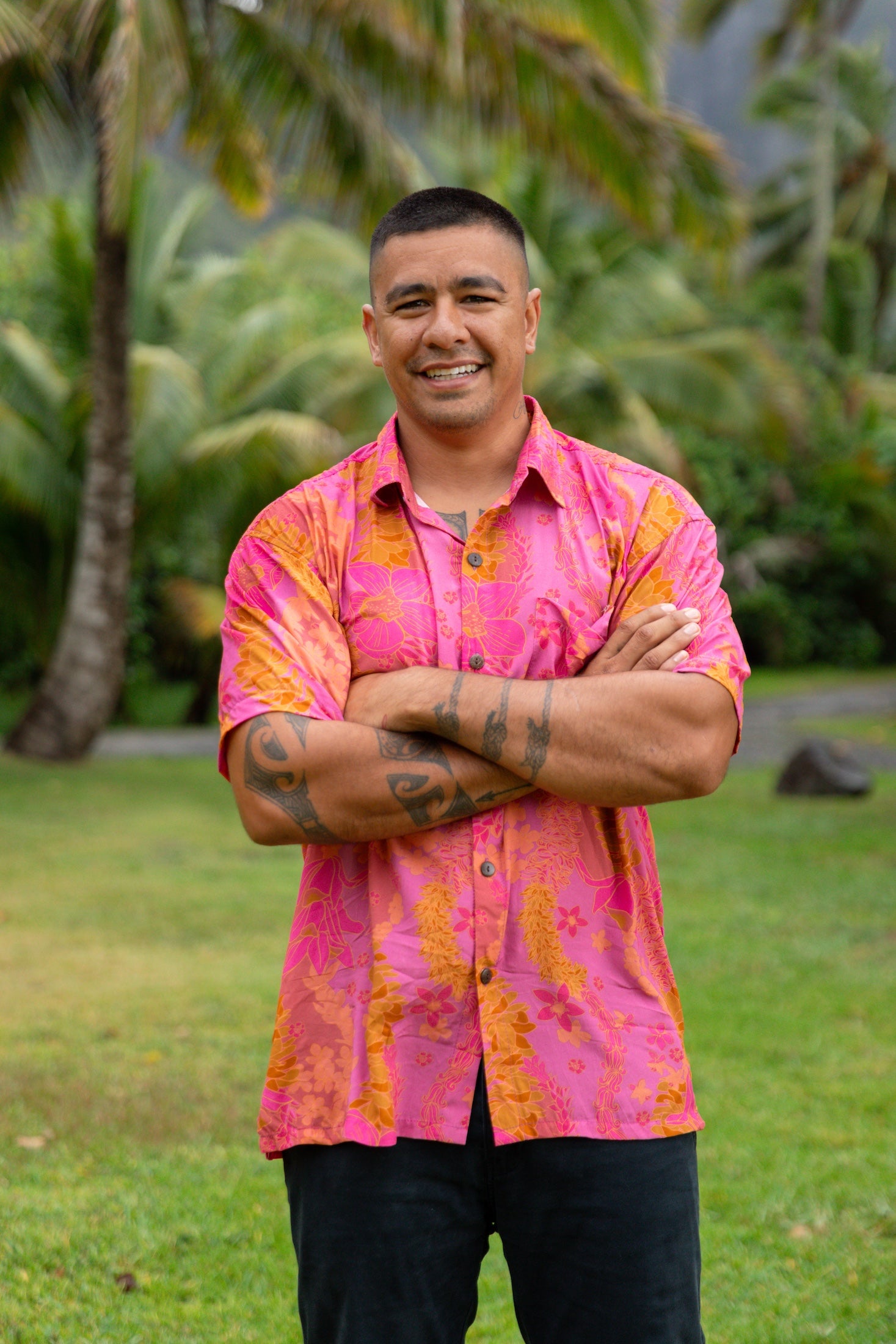 man wearing pink aloha button up shirt with lei strands