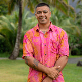 man wearing pink aloha button up shirt with lei strands