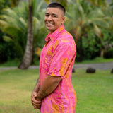 man wearing pink aloha button up shirt with lei strands