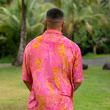 man wearing pink aloha button up shirt with lei strands