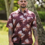 man wearing brown button up aloha shirt with protea print
