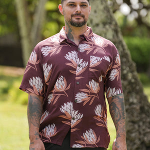 man wearing brown button up aloha shirt with protea print