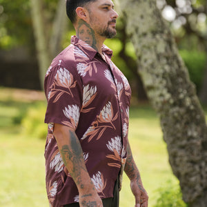 man wearing brown button up aloha shirt with protea print