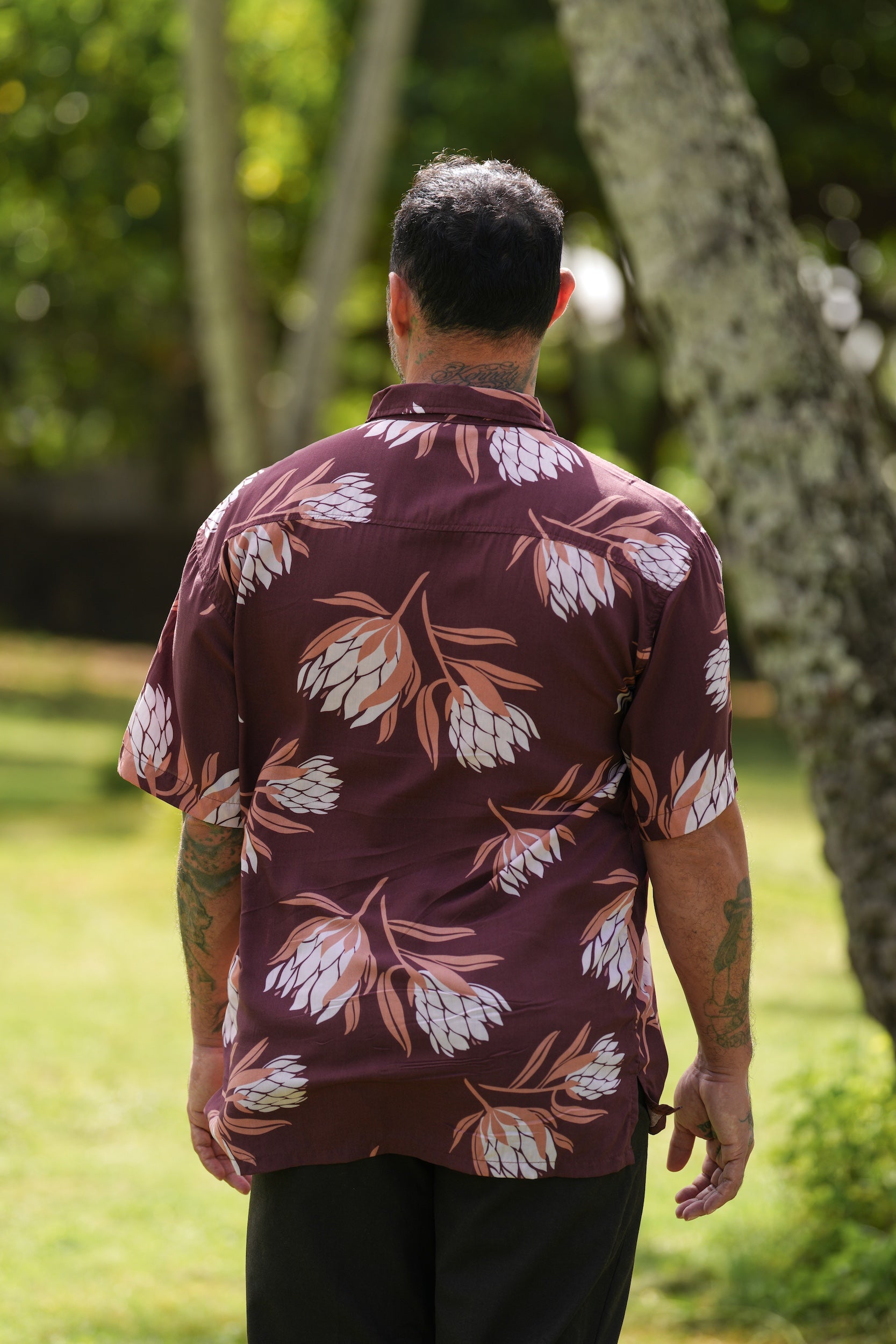 man wearing brown button up aloha shirt with protea print