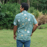 man wearing lush green aloha button-up shirt with pua kenikeni print