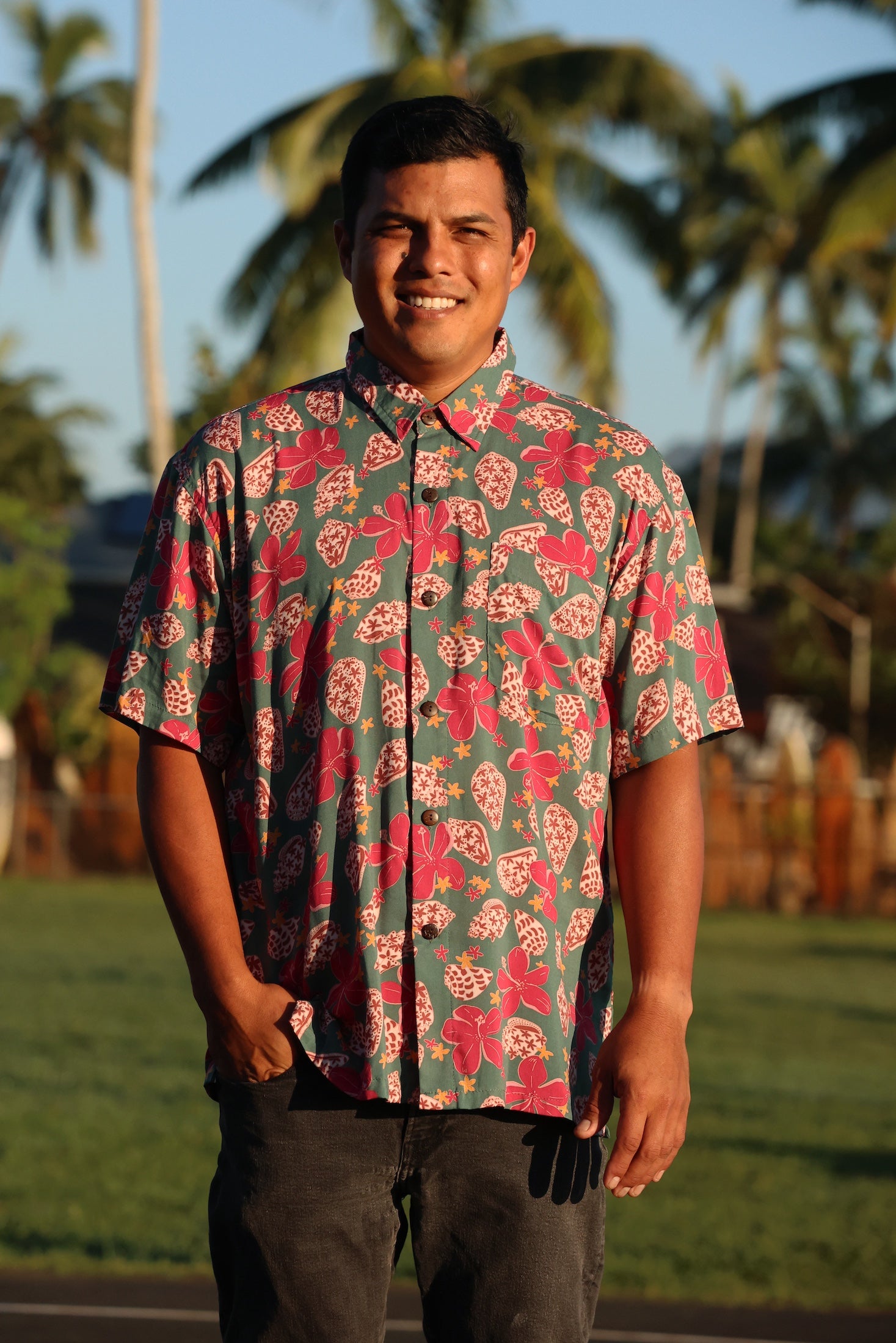 man wearing a teal aloha shirt with shell and pua print