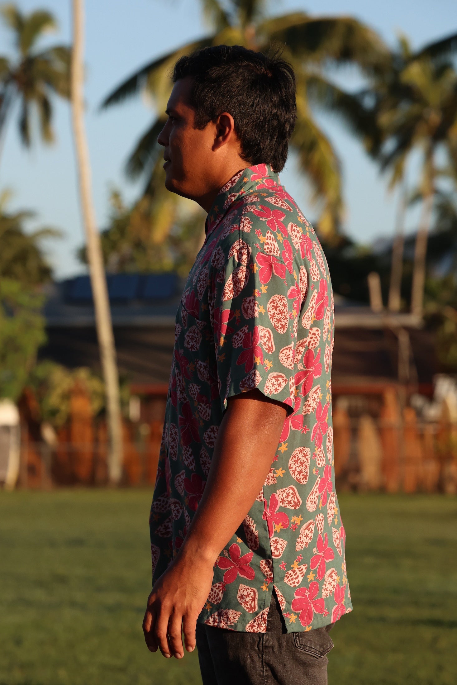 man wearing a teal aloha shirt with shell and pua print