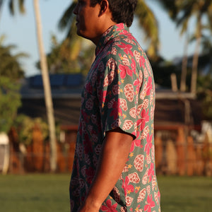 man wearing a teal aloha shirt with shell and pua print