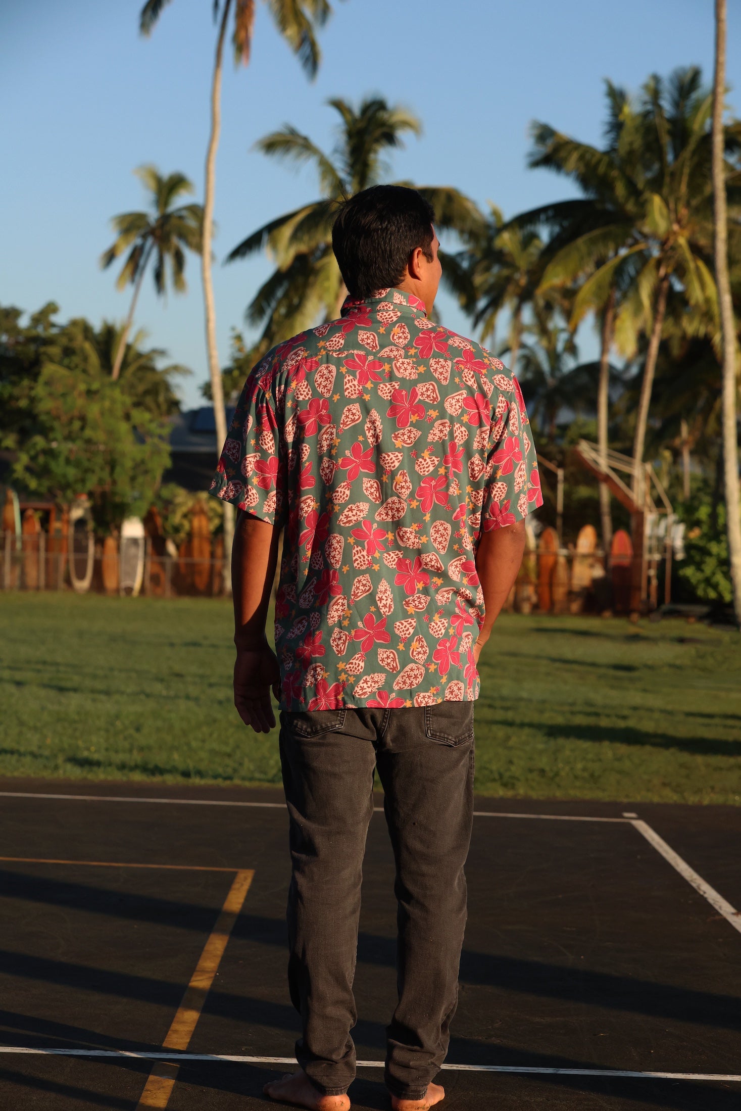 man wearing a teal aloha shirt with shell and pua print