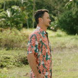 man wearing an aloha button up shirt with red ginger and tiare print