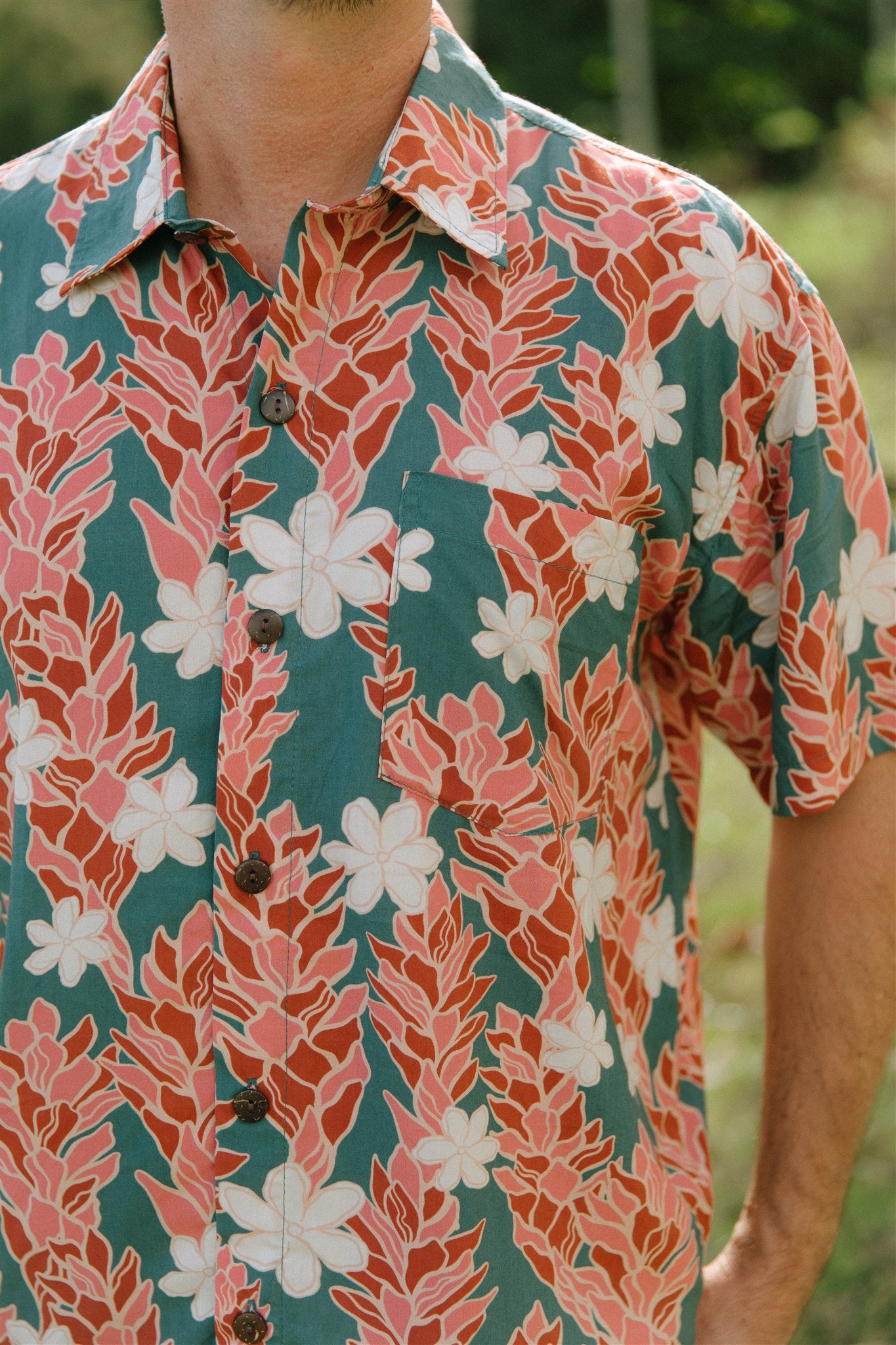 man wearing an aloha button up shirt with red ginger and tiare print