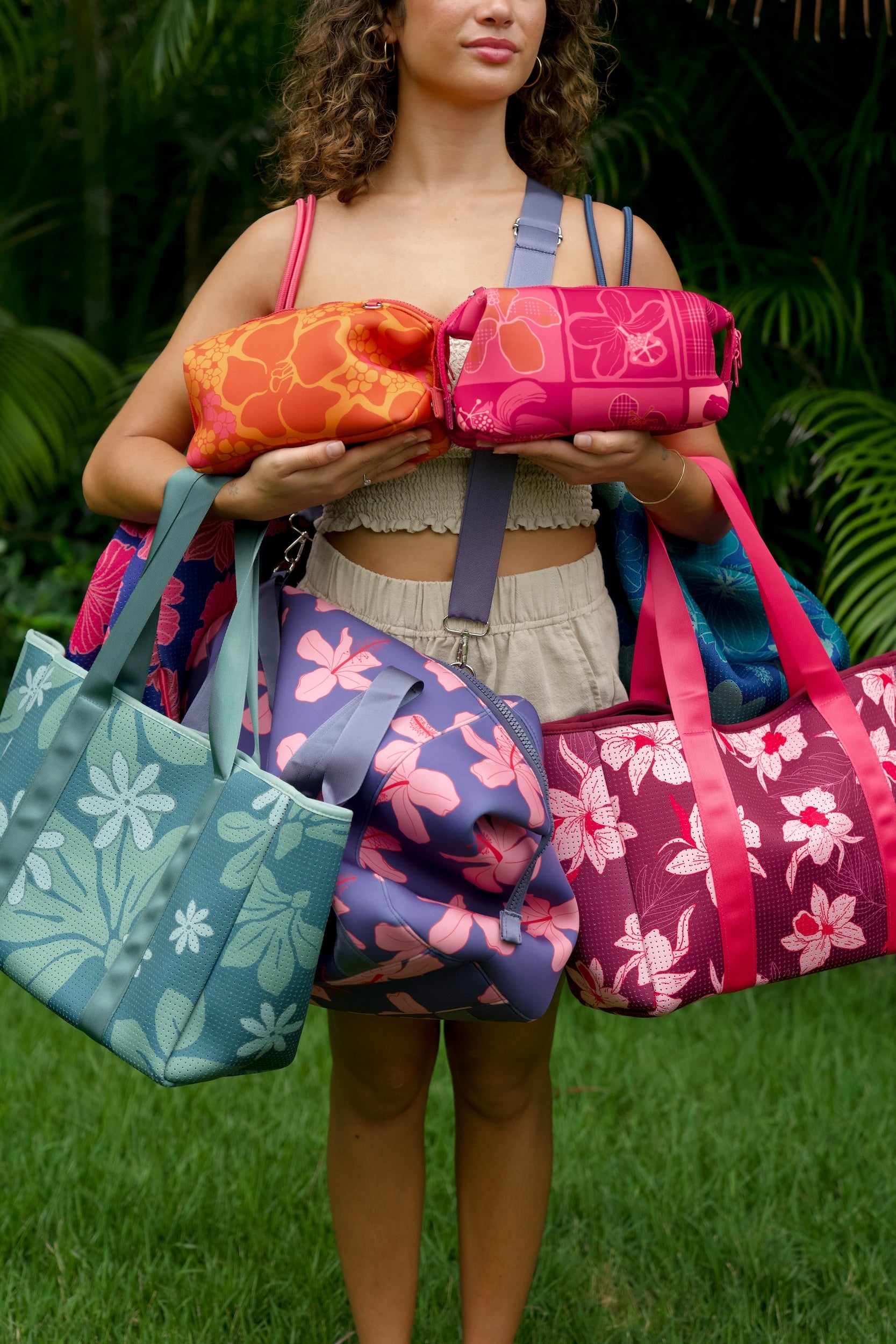 woman holding an expandable neoprene travel pouch with palaka and kokio print