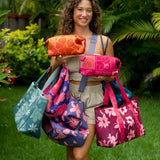 woman holding expandable puakenikeni printed neoprene pouch with detachable mini pouches