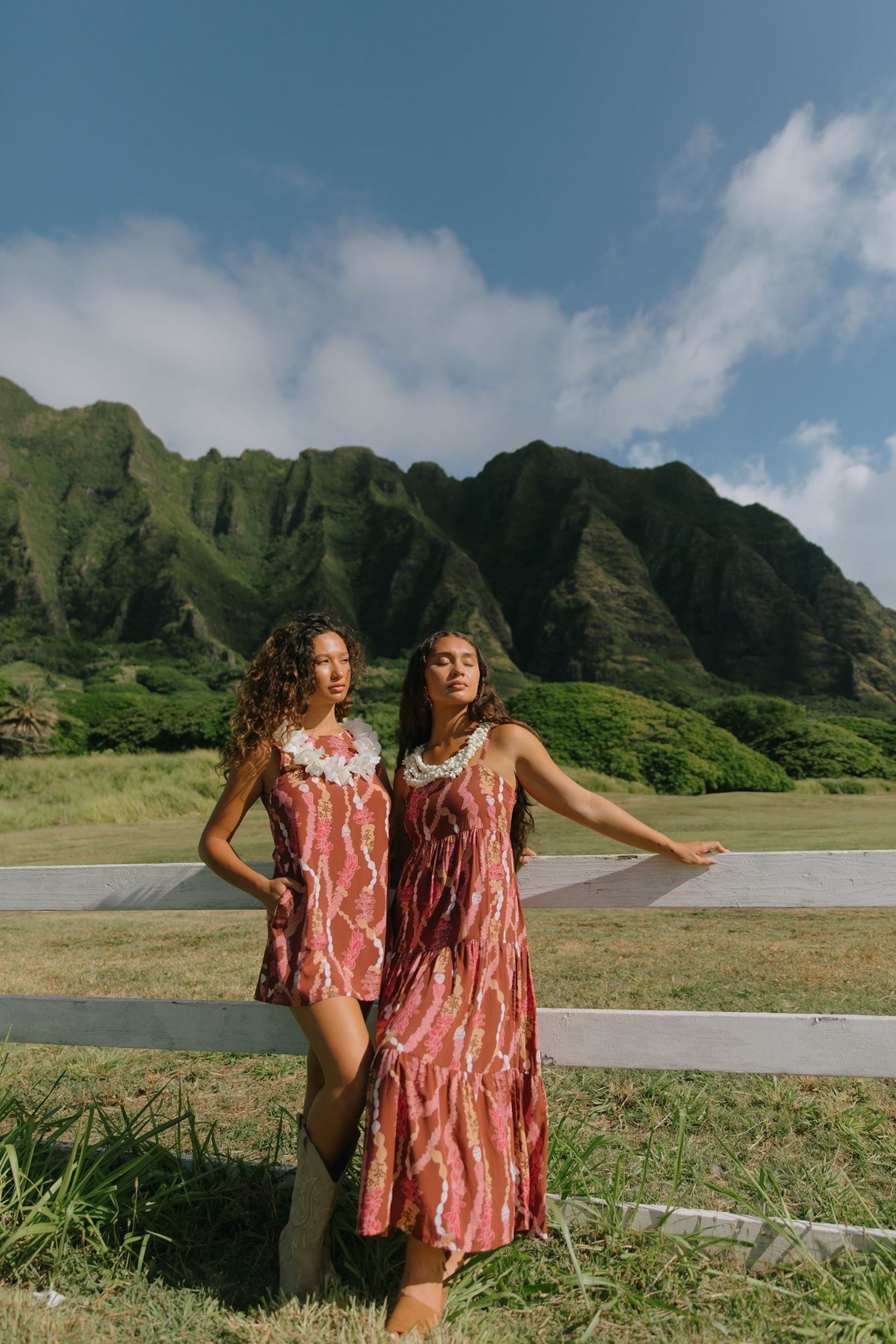 woman with brown hair wearing red-brown maxi dress with lei print