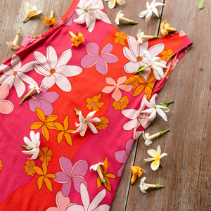 woman with brown hair wearing a pink high neck scoop back mini dress with retro flower print