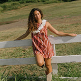 woman with brown hair wearing red-brown high neck scoop back dress with lei print