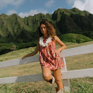 woman with brown hair wearing red-brown high neck scoop back dress with lei print