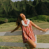 woman with brown hair wearing red-brown high neck scoop back dress with lei print