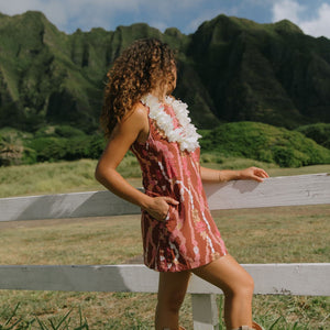 woman with brown hair wearing red-brown high neck scoop back dress with lei print