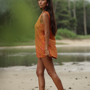 woman with brown hair wearing a retro orange mini scoop back dress with puakenikeni print