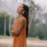 woman with brown hair wearing a retro orange mini scoop back dress with puakenikeni print
