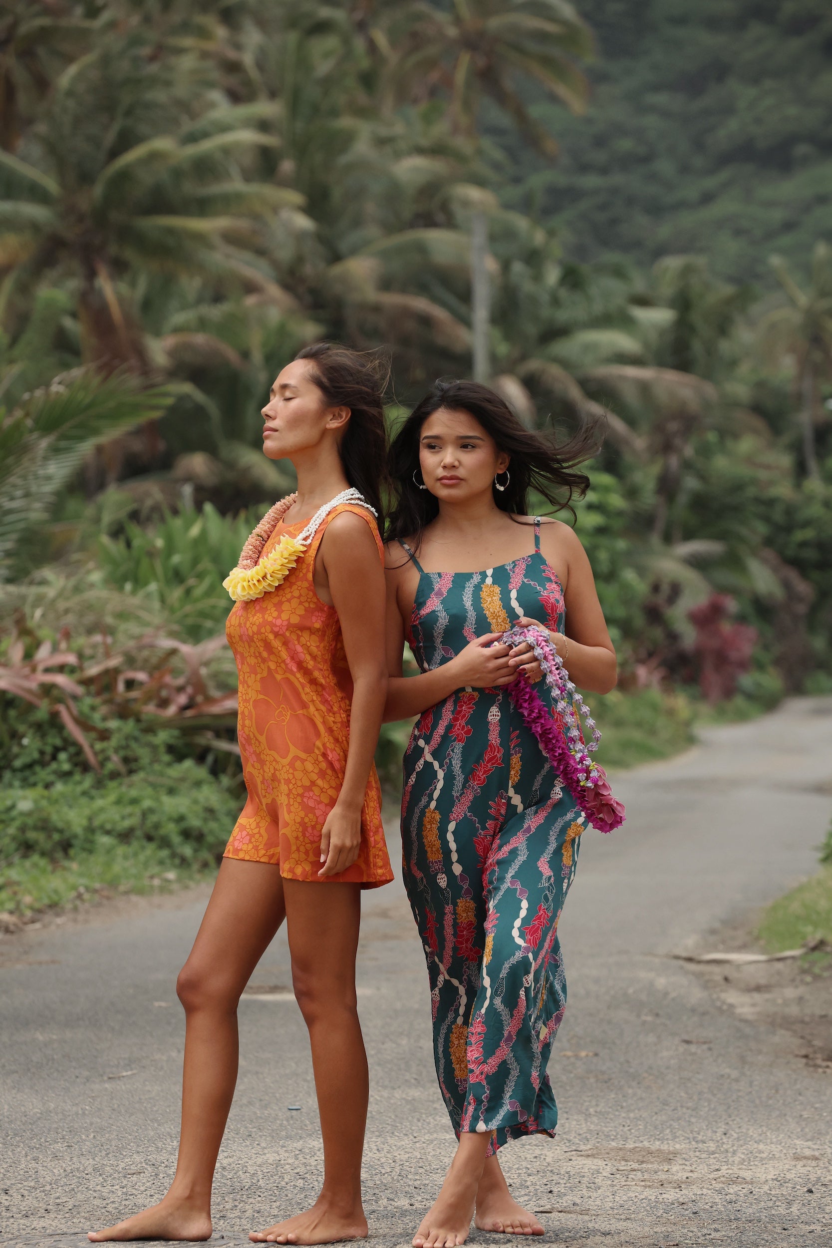 woman with brown hair wearing dark teal high neck jumpsuit with shell lei print