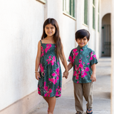 little girl with brown hair wearing a smocked spaghetti strap dress with fern and ginger print