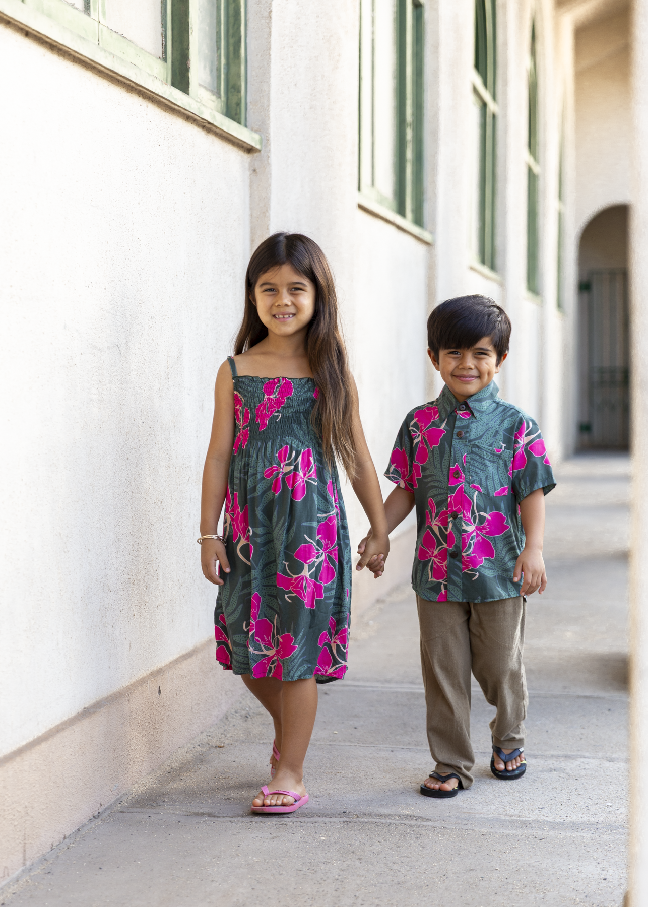 little girl with brown hair wearing a smocked spaghetti strap dress with fern and ginger print