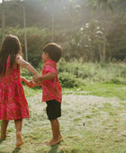 Boy in brown button up shirt with large pink floral print and girl in brown dress with large pink floral print