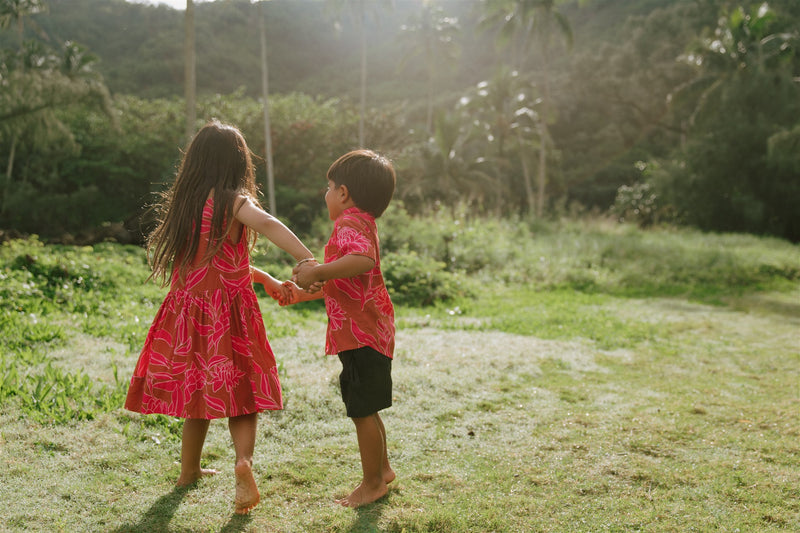 Boy in brown button up shirt with large pink floral print and girl in brown dress with large pink floral print