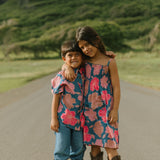little girl wearing a navy spaghetti strap dress with bright pink hibiscus print