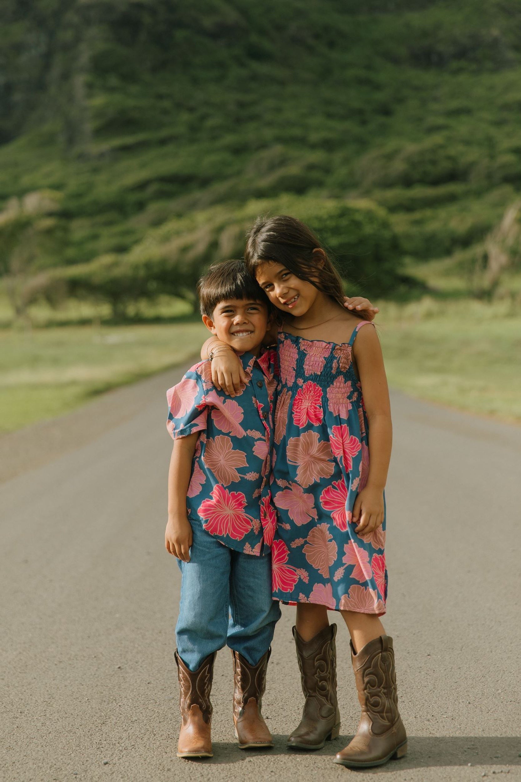 little girl wearing a navy spaghetti strap dress with bright pink hibiscus print