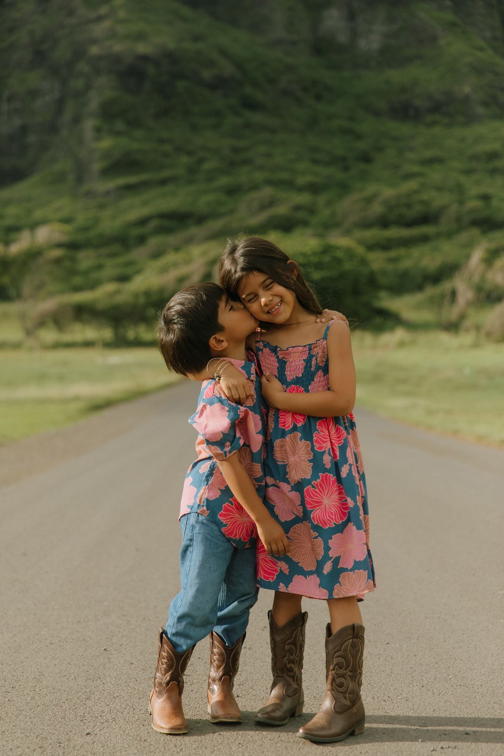 little girl wearing a navy spaghetti strap dress with bright pink hibiscus print