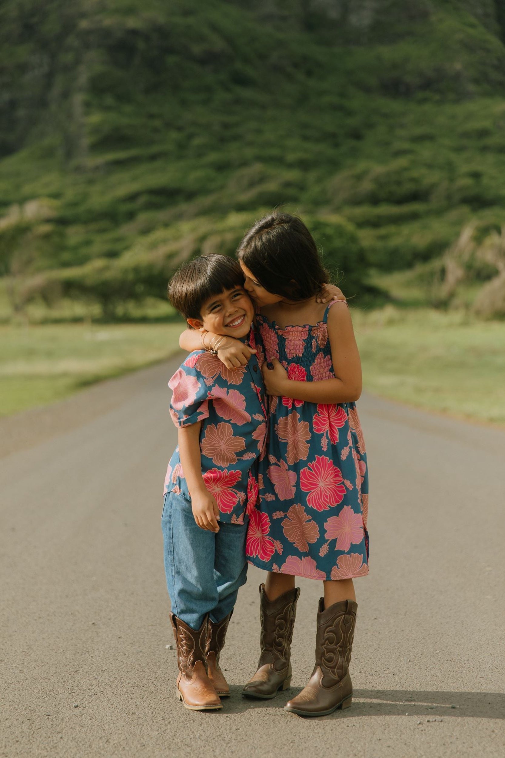 little boy wearing a nevy button up aloha shirt with bright pink hibiscus print
